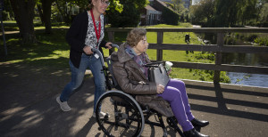 Dame duwt andere dame in rolstoel over bruggetje.jpg